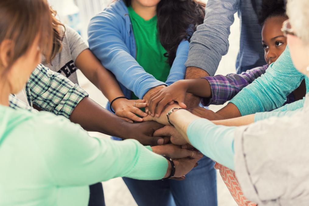 A group of students and social workers with an "all hands" in group.