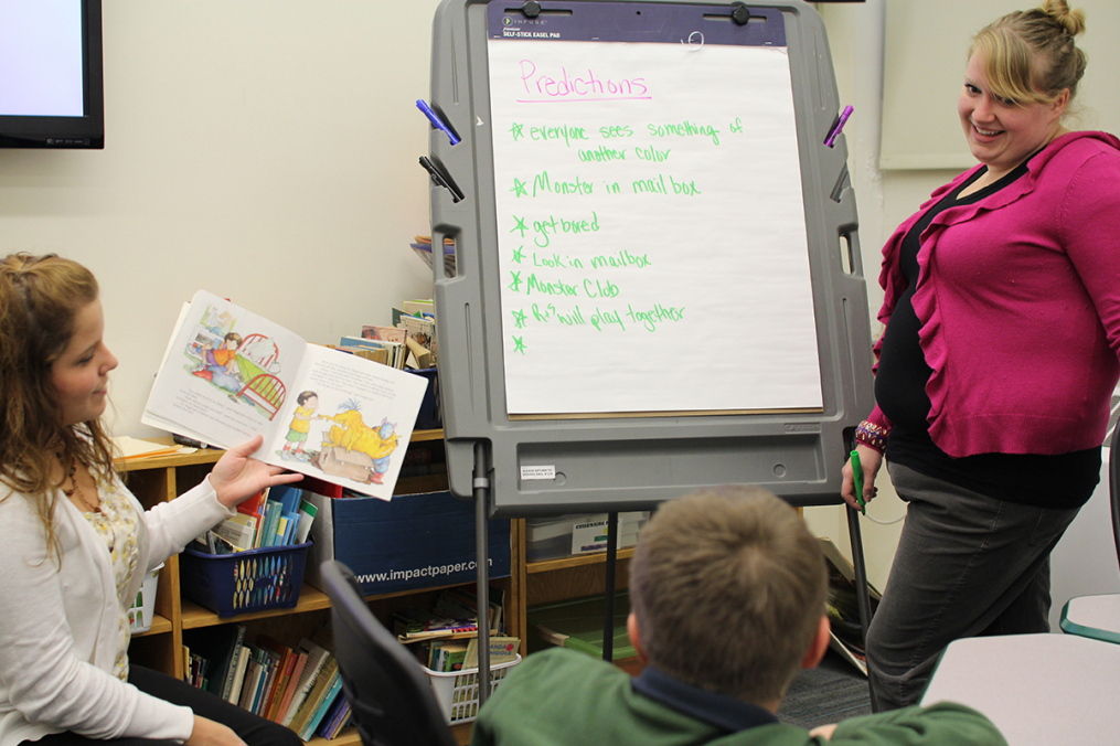 A teacher stands near an easel