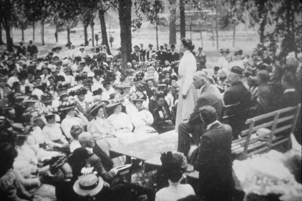 woman standing in front of a crowd talking to them