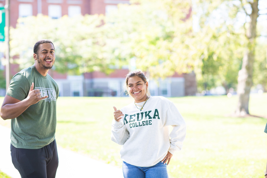 Two HEOP students giving a thumbs up with Ball Hall in the backdrop