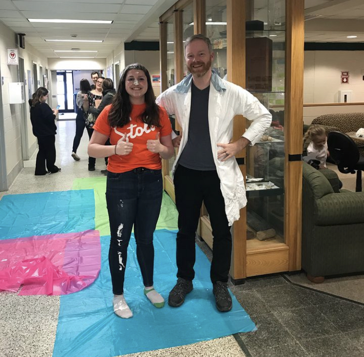 Brianna and Dr. Robak posing together after a pie to the face at the science club fundraiser