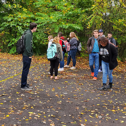 students in a parking lot looking for evidence in a setup crime scene